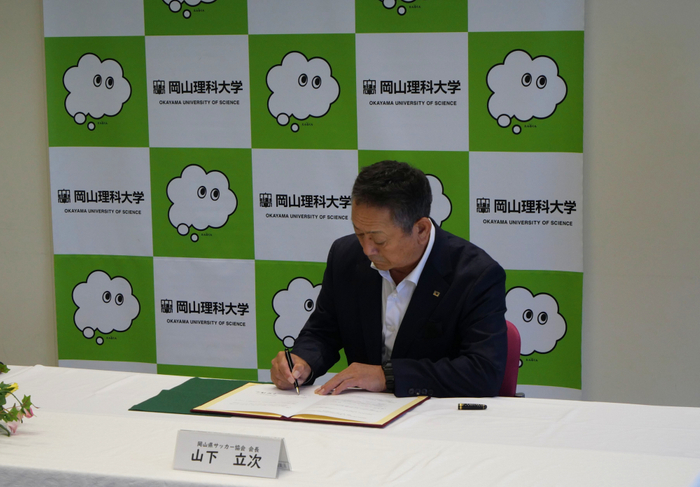 協定書に署名する山下会長