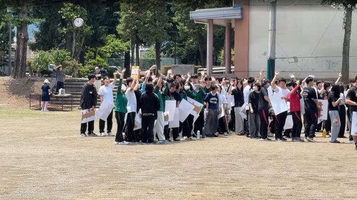 人文字の参加者がドローンに手を振る姿