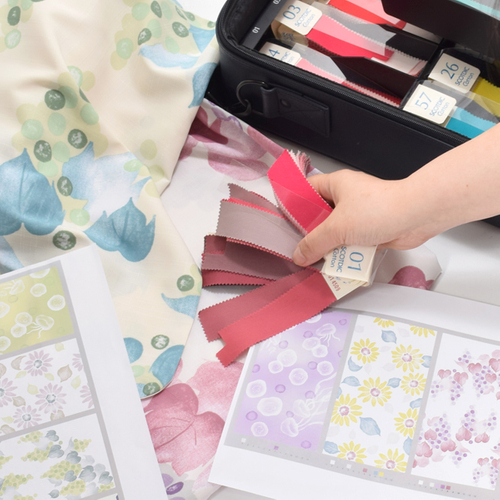 色チップを当てて検討する様子（図案は2023年版）