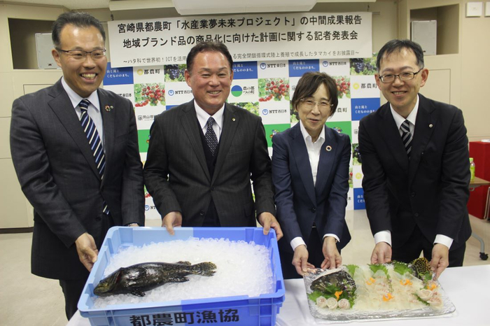 成長したタマカイを前に笑顔の(左から)小林担当部長、坂田町長、南副学長、大友副支店長
