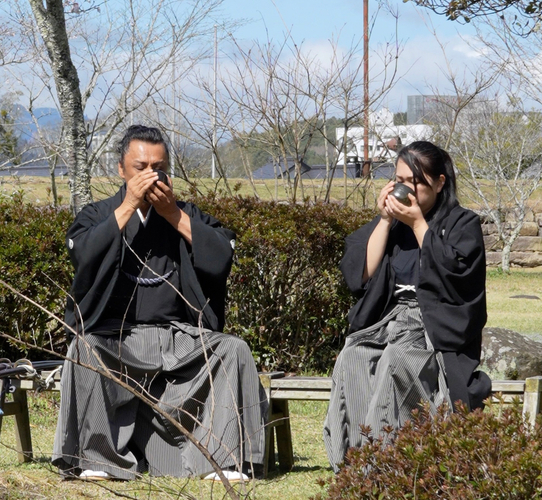&rarr;三日月ノ城(人吉城・国史跡)に鎮座する相良神社で抹茶を召し上がる 兵法タイ捨流 第15代目宗家・上原エリ子さま(写真：右)、兵法タイ捨流 龍泉館館長・山本隆博さま