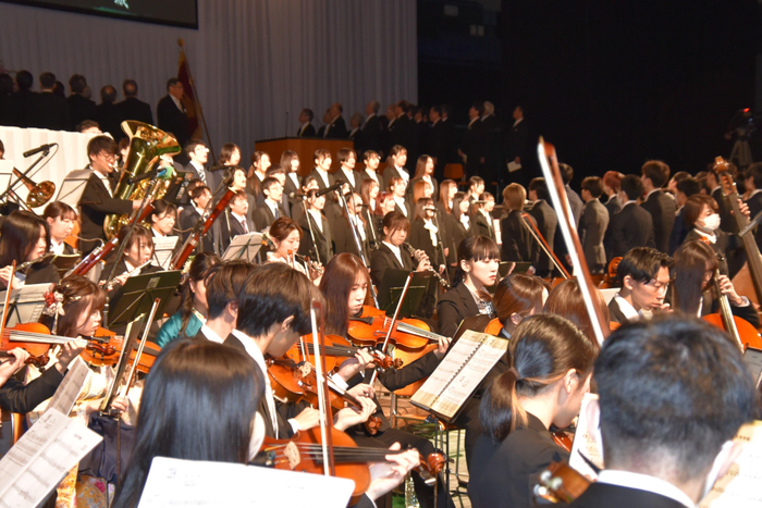 「はもりね」の歌声と管弦楽団の演奏で学歌を斉唱