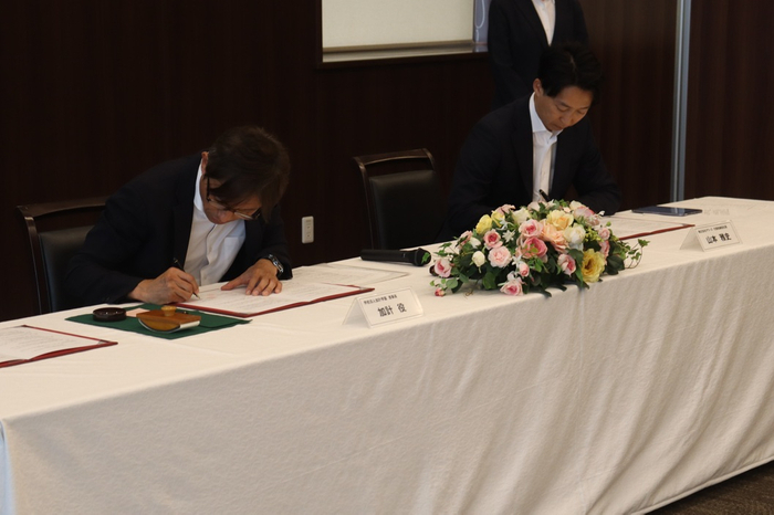 協定書に署名する（左から）加計理事長、山本社長