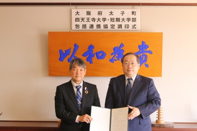 太子町の田中 祐二町長(左)と、須原 祥二学長(右) ＝ 12月15日(木)、背景の「以和為貴」は17条憲法の第1条「和を以て貴しとなす」