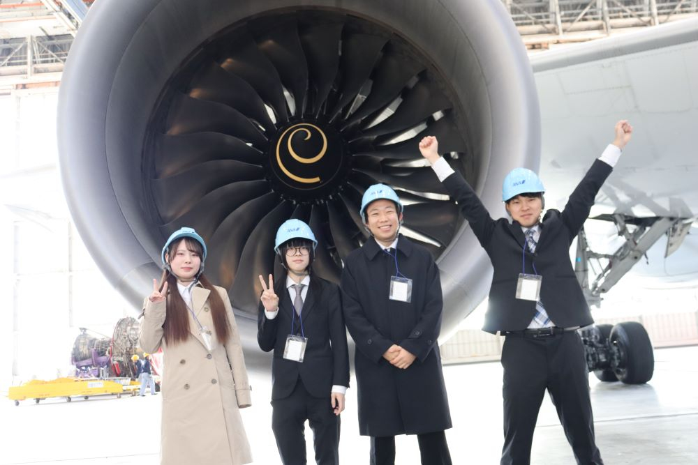 エンジンの前でポーズを取る学生たち