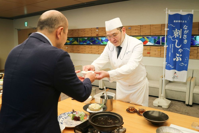 「夏限定 ながさき刺しゃぶ完成報告会」にて、 鈴木史朗長崎市長（左）へ新メニューを紹介する様子