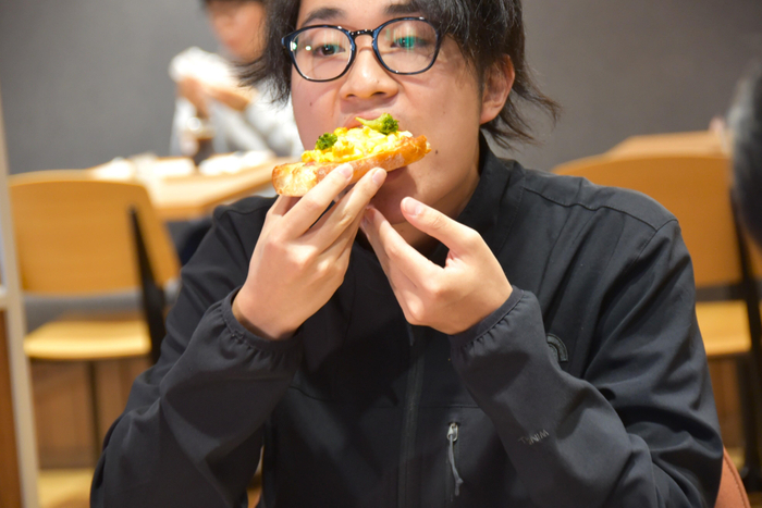 ボリューム感のあるオープンサンドをほおばる学生