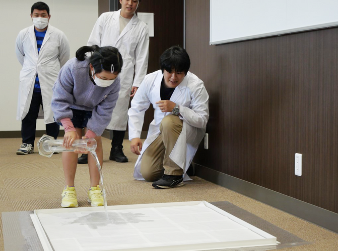雨量1ミリメートルの水量を体験してみる小学生の参加者