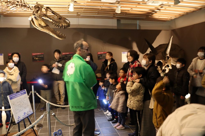 藤田館長（後ろ姿）の説明に聞き入るナイトツアー参加者