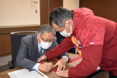 たすきに激励のメッセージを書く野口学長