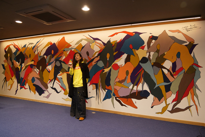 ウォールアートを前に冨永ボンド氏記念撮影