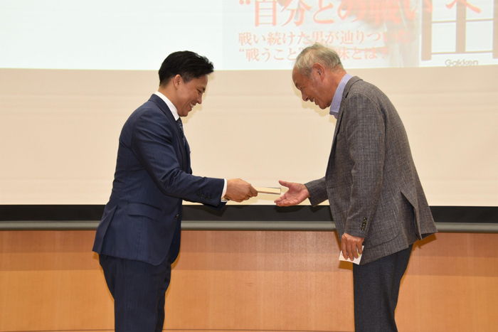 当選者に著書を贈る野村特任教授（左）