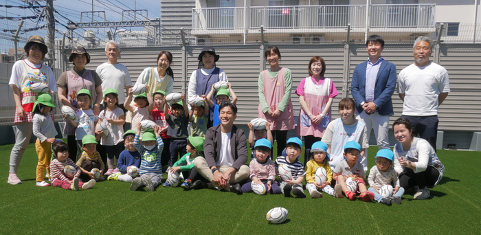 (保育園の園児たちに囲まれて写真撮影をする廣瀬氏<中央>)