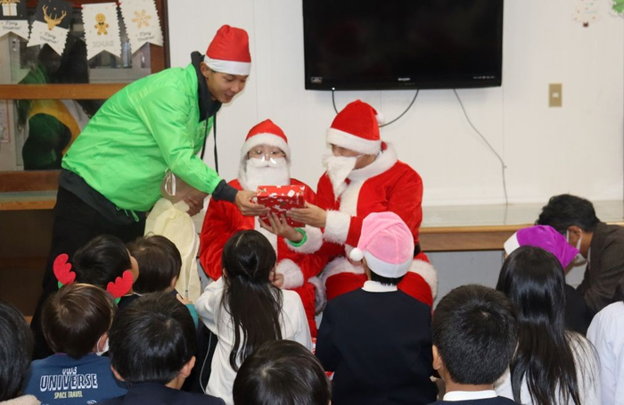 子どもたちにプレゼントを手渡す学生サンタさん
