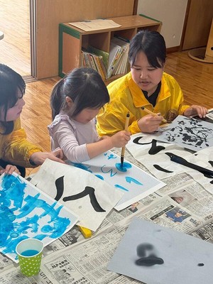 書道を楽しむ子どもを見守る