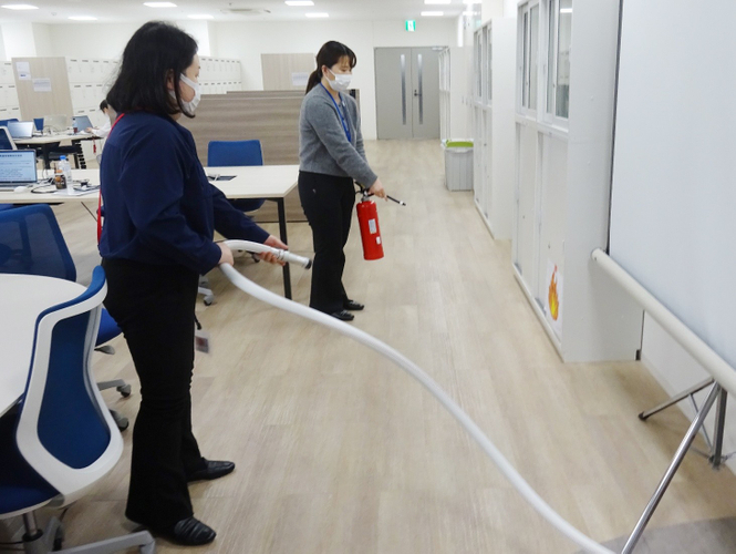 モバイルバッテリー火災を想定した消火訓練を行う医誠会国際総合病院の職員(大阪市北区)