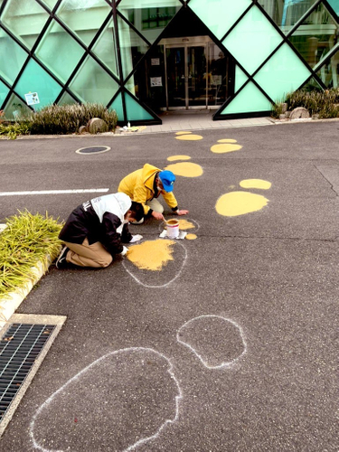 路面にペイントする石垣館長（右）と生物地球学科３年の岩本侑己さん＝12月24日