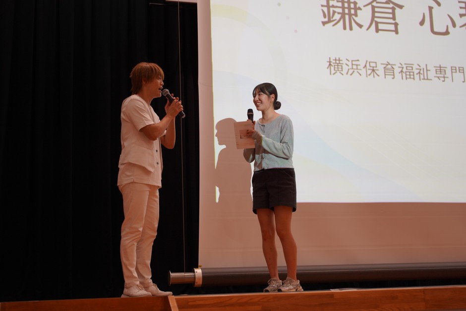 司会のおばたのお兄さんが保護者役を務めたロールプレイ競技。保護者への伝え方まで含めて保育者としての判断を表現した。写真右は大賞の鎌倉 心琴さん。