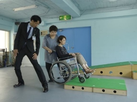 車いす使用者の介助（提供：公益財団法人日本ケアフィット共育機構）