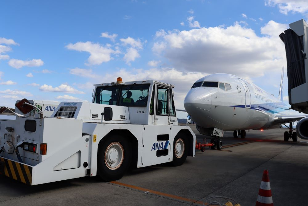 羽田便を駐機場から誘導路へ押し出すトーイングカー