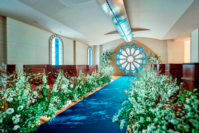 &rdquo;青いバラ&rdquo;をモチーフにラピスラズリを用いて作られたステンドグラスと、ロイヤルブルーのバージンロードが印象的なチャペル