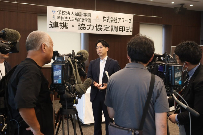 マスコミの囲み取材に答える山本社長（中央）