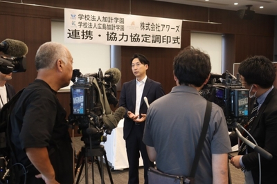 マスコミの囲み取材に答える山本社長(中央)