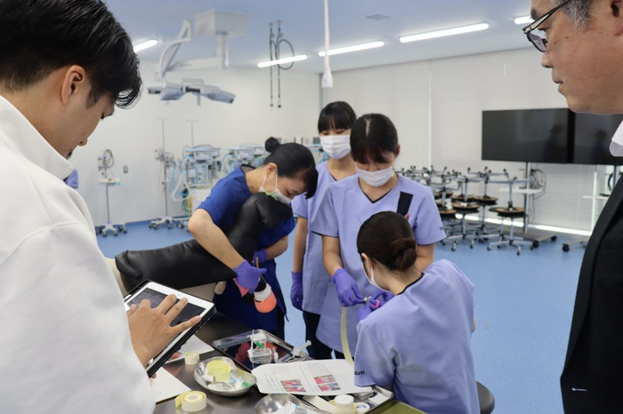 動物看護実習で、包帯巻圧計測装置の動作状況を確認する情報理工学科の赤木徹也教授（右）と大学院理工学研究科の石橋卓実さん（左）