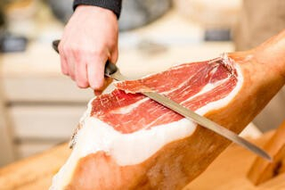 原木の生ハムを手切りでカット