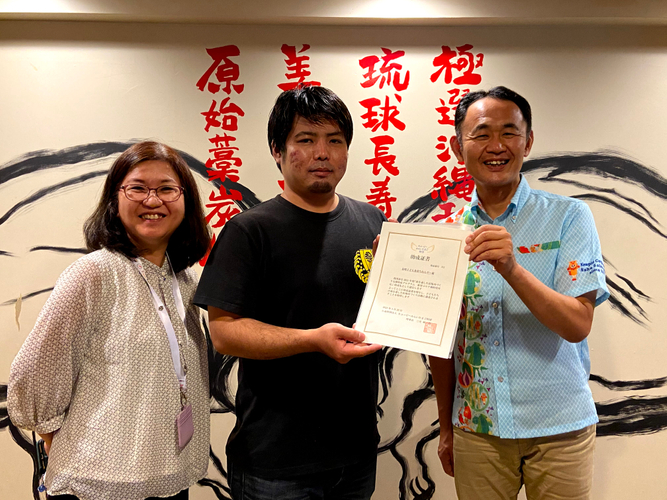 助成証書の授与（沖縄県で実施） プログラムB助成団体代表の泉崎子ども食堂ちねんや～代表者（写真左・中）と キユーピー那覇営業所長（写真右）