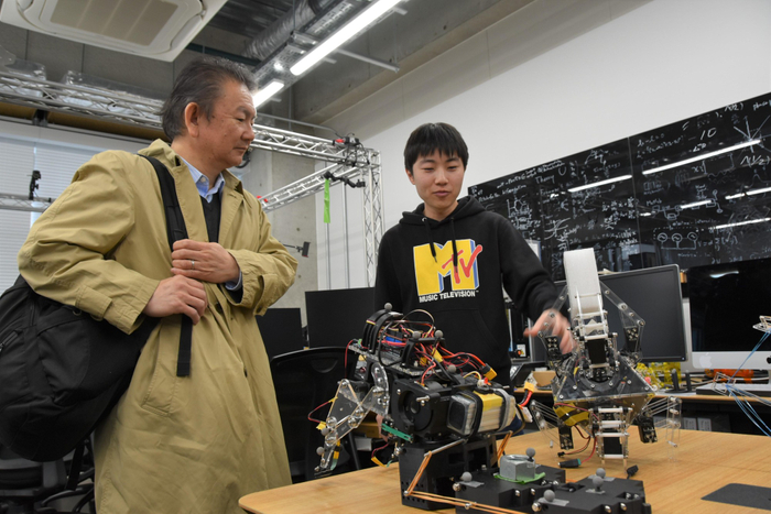 池本研究室でロボットを手に説明する学生