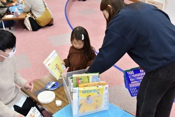 ブックバッグにする絵本の表紙を迷いながら選ぶ子供