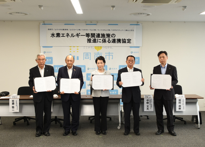 協定書を掲げる関係者