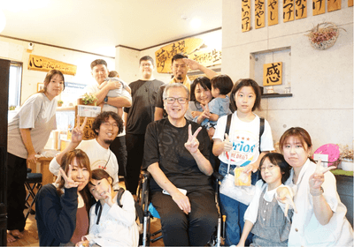 今回の外出に参加したご本人、ご家族、リハビリ職員、店主ら。地域とのつながりから実現した、念願の「いこい」でのひととき。