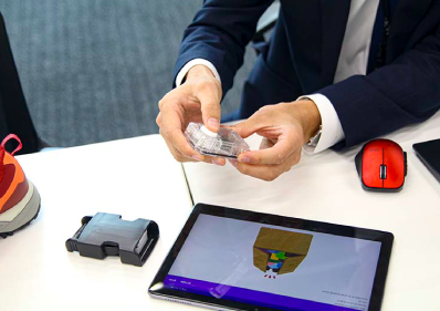 廣野氏が持っているのが「無線・電池レスデバイス」のデモ機。ボタンを押す・指を離すと電波を発信し、タブレット内の箱のイラストが開閉する